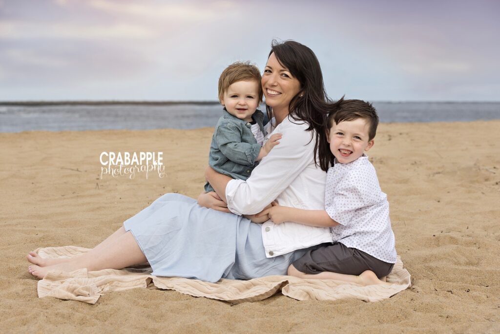 Mother and two sons sitting in the sand during joyful family beach session

