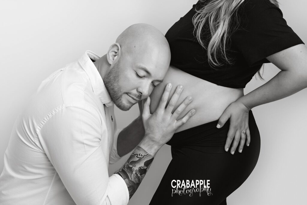 Black and white photo of dad resting head on baby bump – Maternity Photography Studio Andover MA