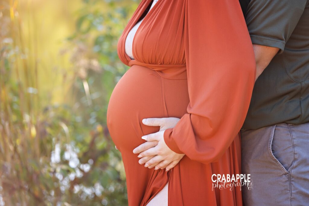 Maternity photo highlighting belly profile in rust-orange gown – Relaxed and Natural Maternity Photo Experience