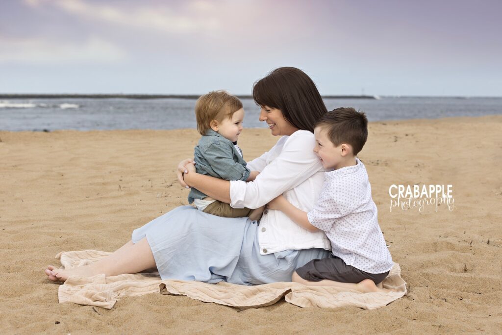 Mom cuddling her two children during a beach family portrait session during a natural family photography session