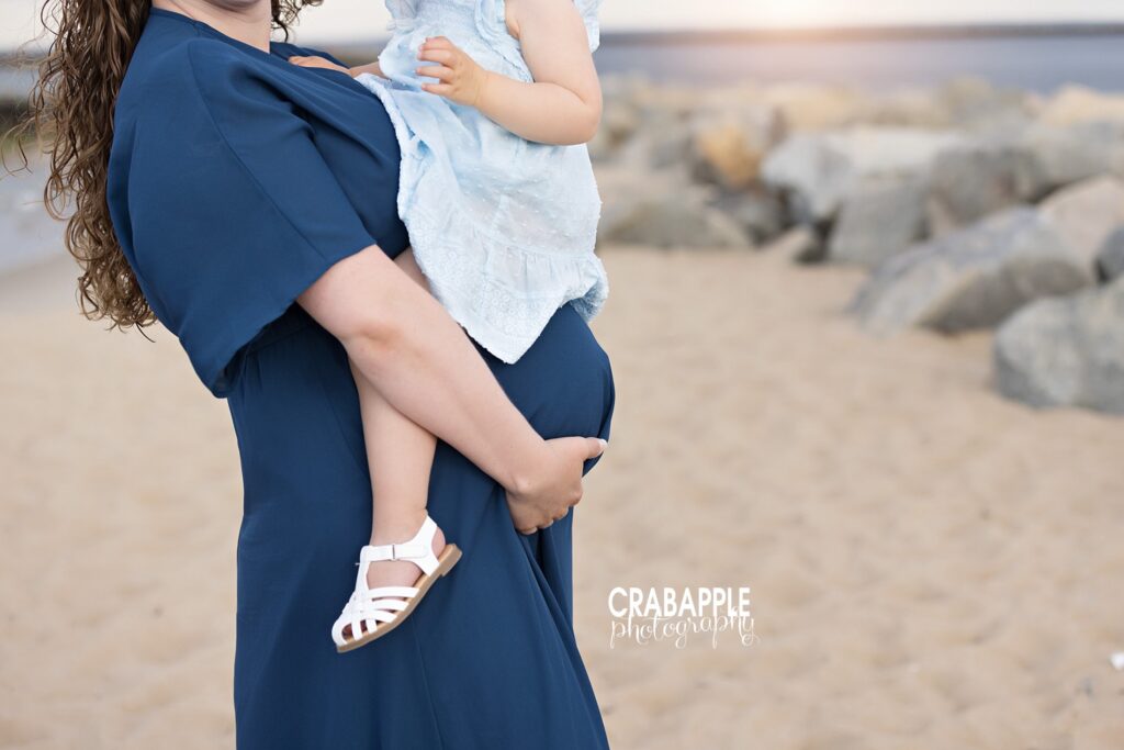 Mom holding toddler on the beach during sunset maternity session -- professional pregnancy photographer 