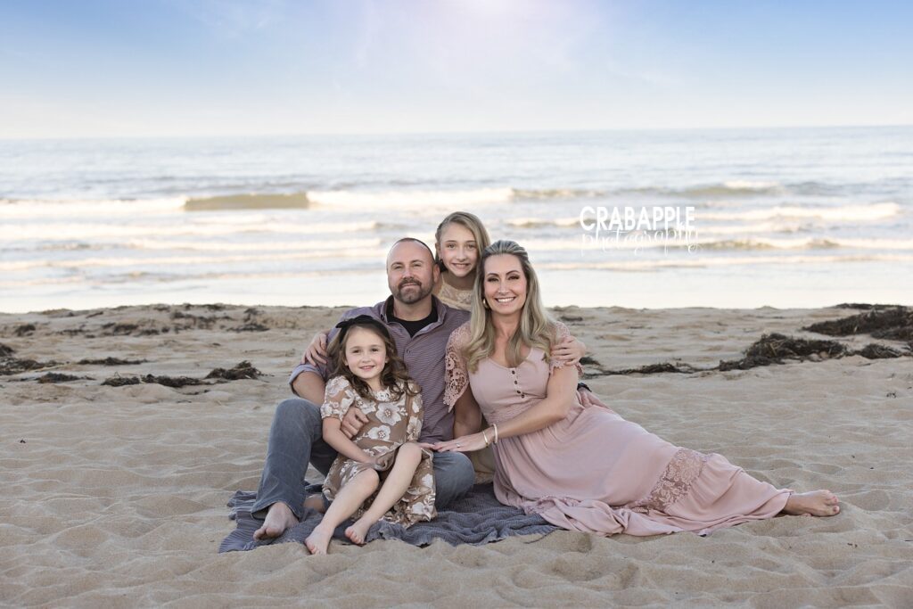 Family sitting and snuggling together on a blanket near the shore