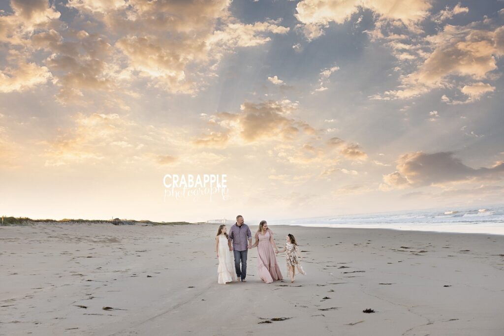 Family walking together on open sandy beach under dramatic sky