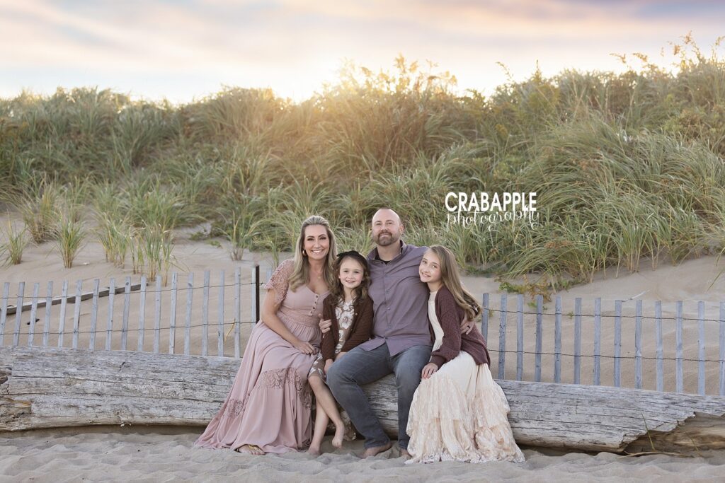 Family smiling together in front of beach grass and dune fencing