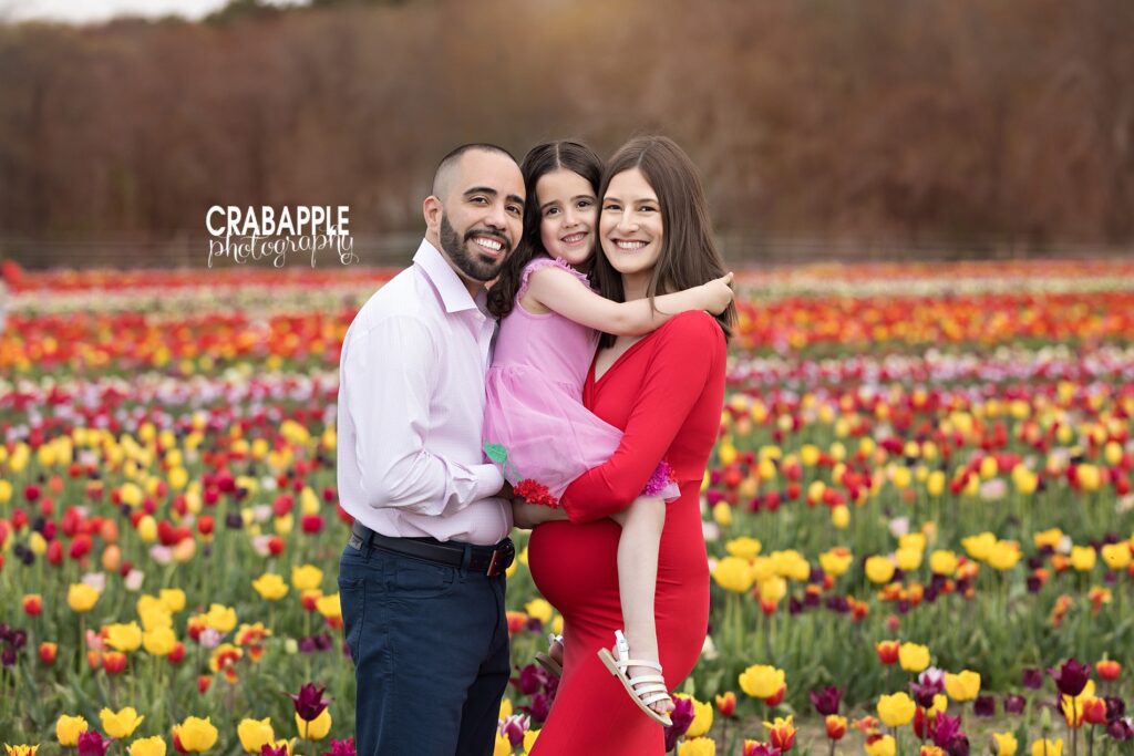 A family hug during a maternity photo session in a tulip field