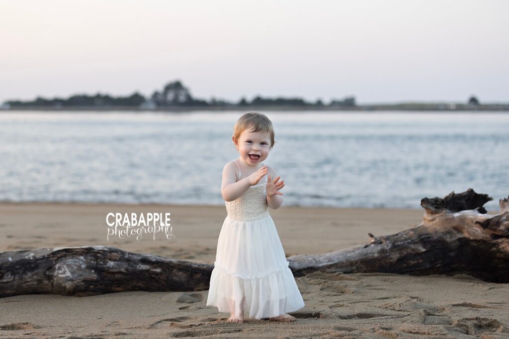 Smiling toddler clapping her hands during a mommy and me beach photo session on the North Shore