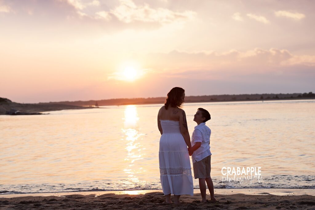 Golden hour mother-son beach photo near Boston MA Mother and son holding hands during golden hour beach photo session in Boston
