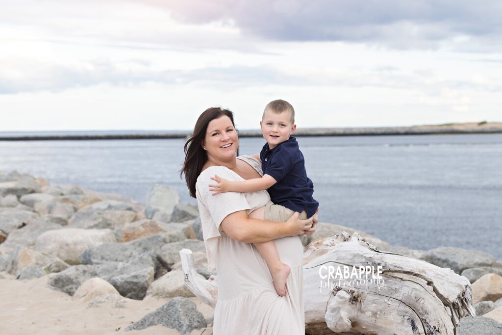 Mother holding toddler son during Boston beach maternity photo session