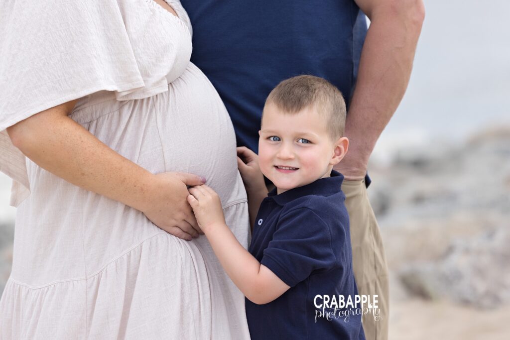 Family of three snuggling during a beach maternity photo session in Boston