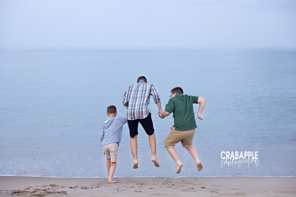 Three brothers jumping over waves during a Boston MA area beach family photo session.