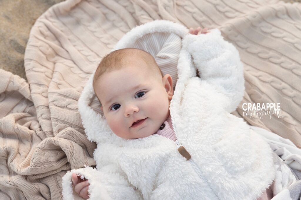 Close-up of a smiling baby laying on a blanket during a golden hour beach portrait session