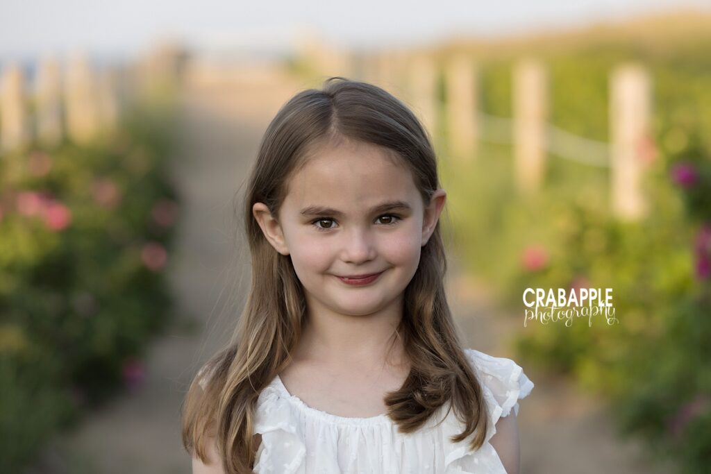 Young girl smiling in a flower-lined path by Salisbury Beach