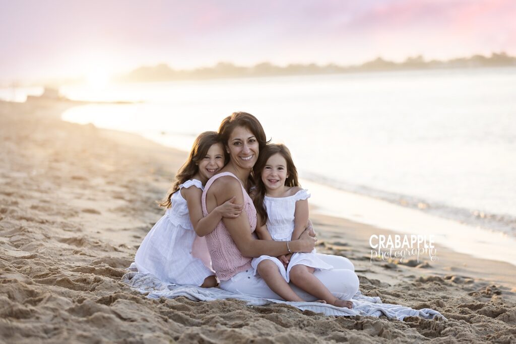 Mom sitting with two children on Salisbury Beach during sunset