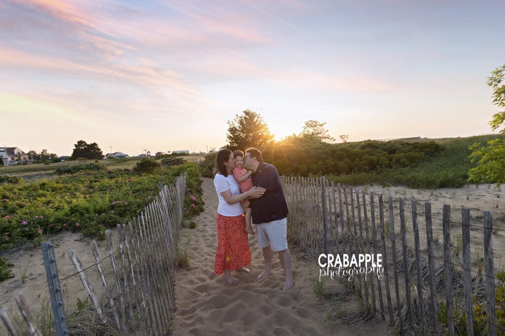 Parents giving son a sweet kiss near dune fence at Salisbury Beach