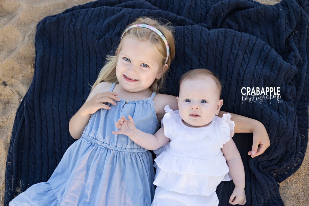 Toddler and baby sister portrait ideas on the beach Toddler sister and baby sister on a beach blanket during beach family photos