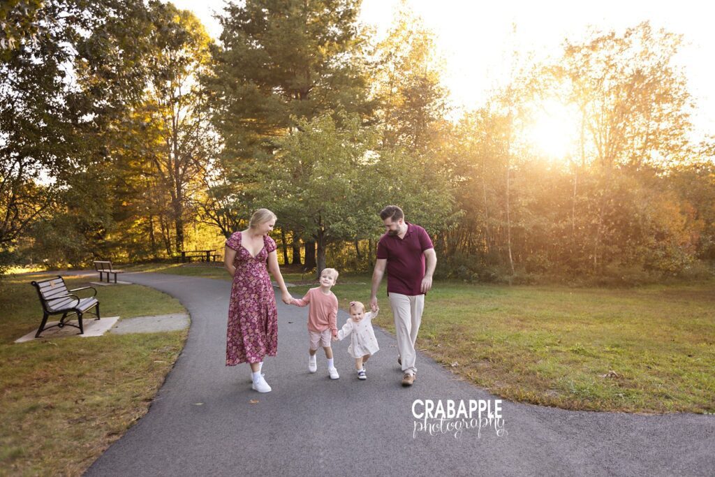 Fall lifestyle family photos Fall lifestyle family portrait of a family of four walking hand in hand along a path in the woods