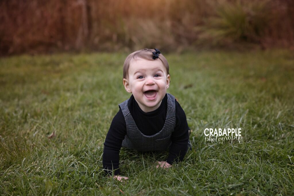 Baby smiles during fall photos in North Reading Smiling one year old baby girl crawling towards the camera during fall portraits outdoors