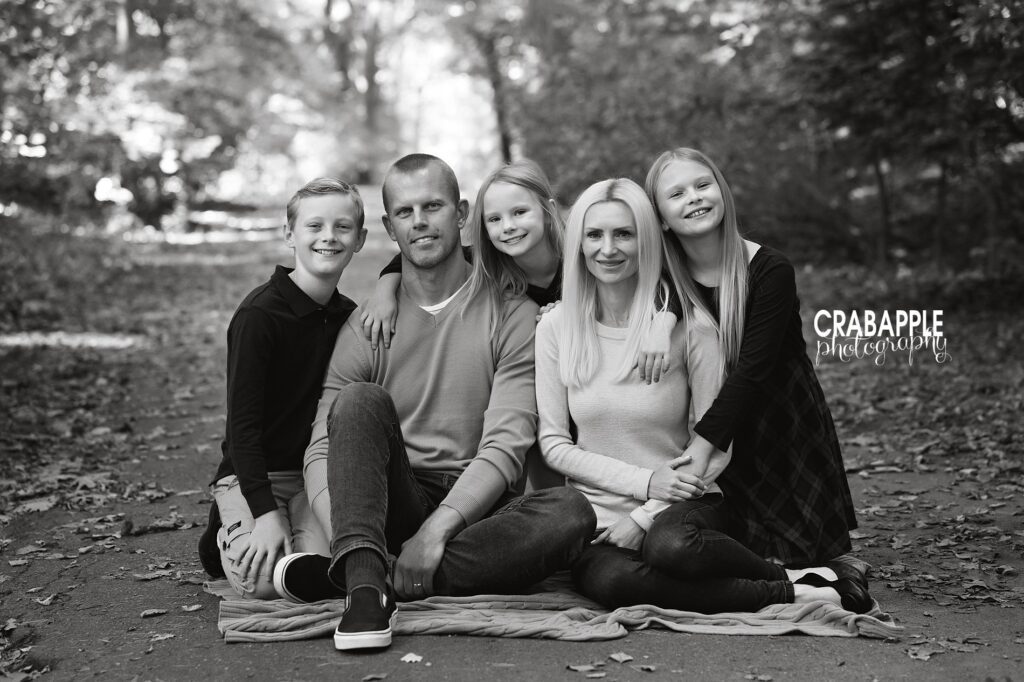 A portrait of a family of five sitting on the ground together during their Boston family photos, in black and white