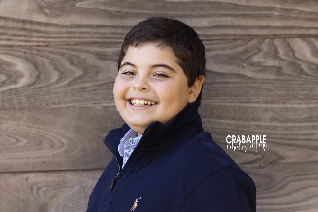 Solo portrait of a young teenage boy in front of a rustic backdrop