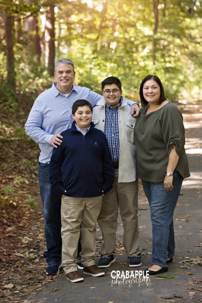 A family of four in classic New England styling smile for the camera during their outdoor fall family portraits