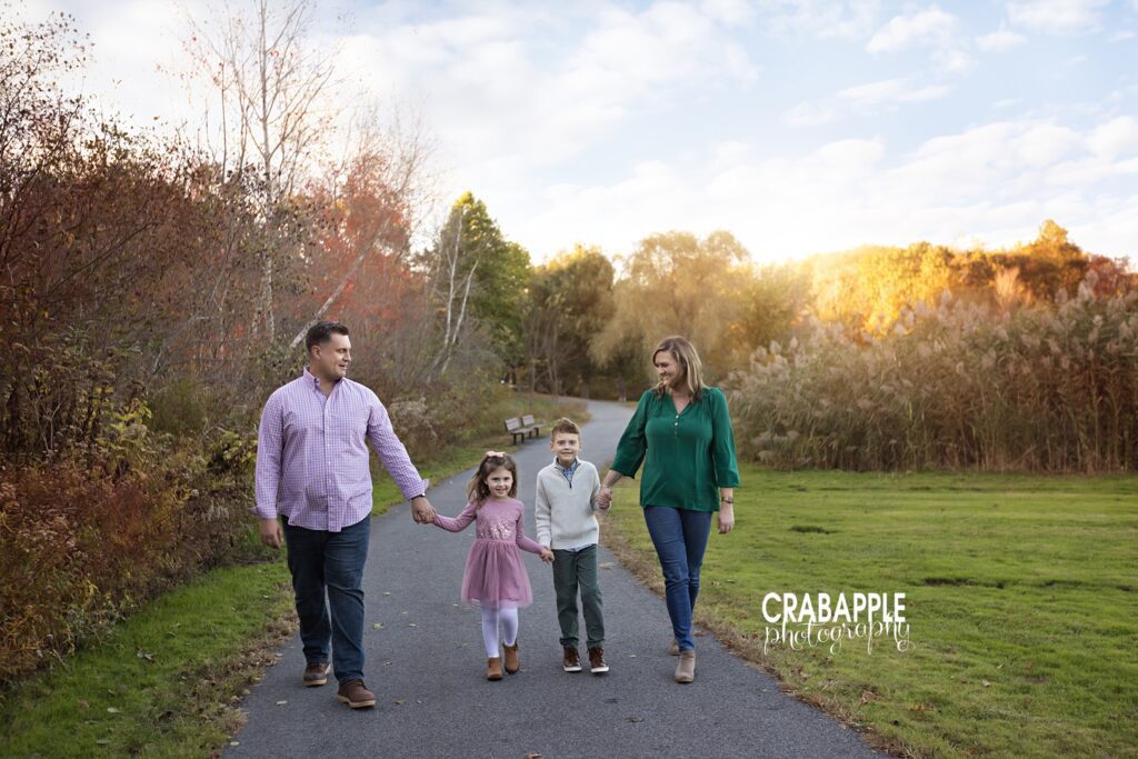 Timeless candid family photo pose idea for fall, family of four holding hands and walking towards camera