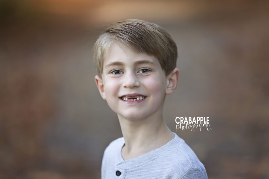 A young boy missing his front teeth smiles at the camera