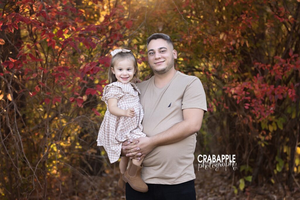 A father and daughter pose for fall family portraits in coordinating cozy neutral outfits in shades of beige and taupe