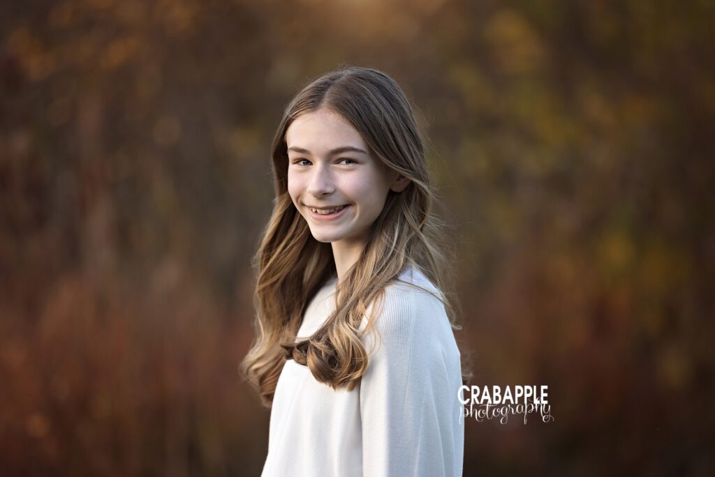 A young girl poses for fall portrait in a light, classic, neutral sweater