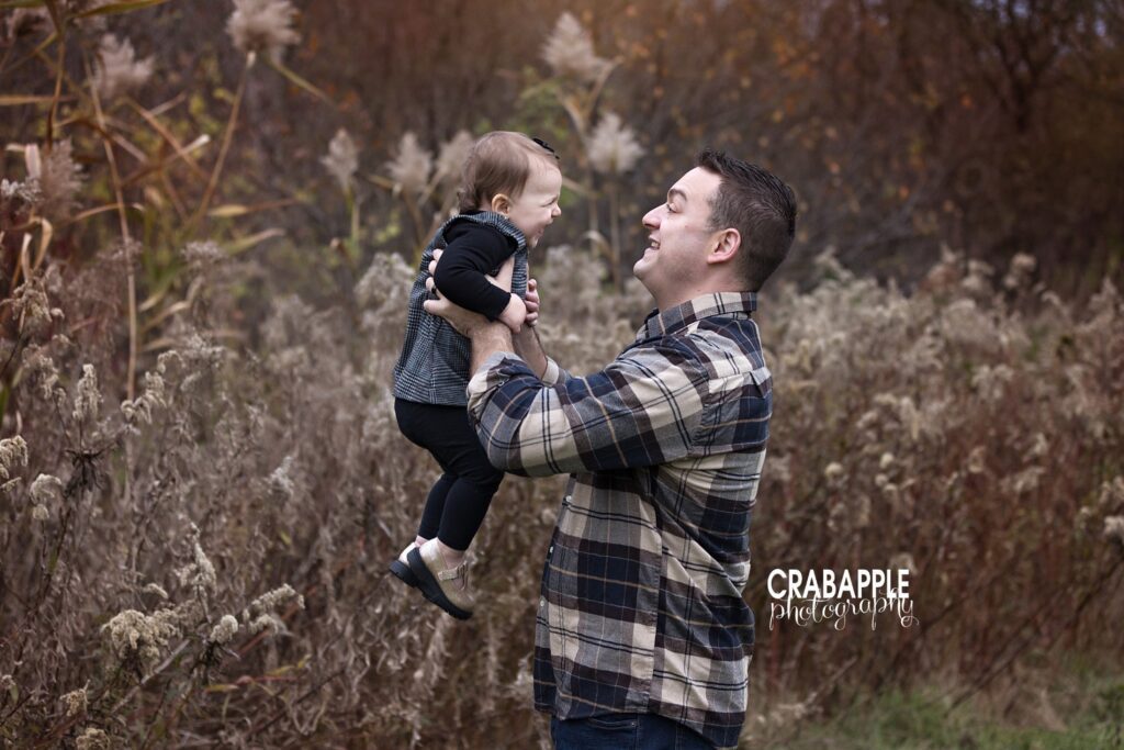 Dad and baby portraits during fall family photos Father holding baby girl during outdoor family session