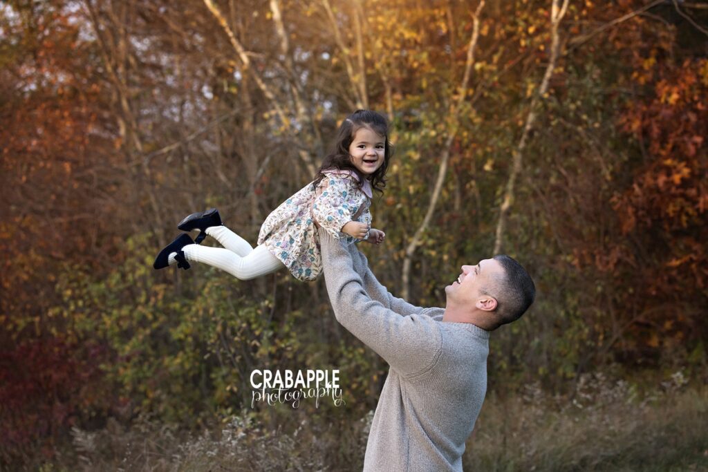 Dad swinging daughter during fall family photos in Andover MA Dad swings his younger daughter during outdoor fall family photos in Andover MA