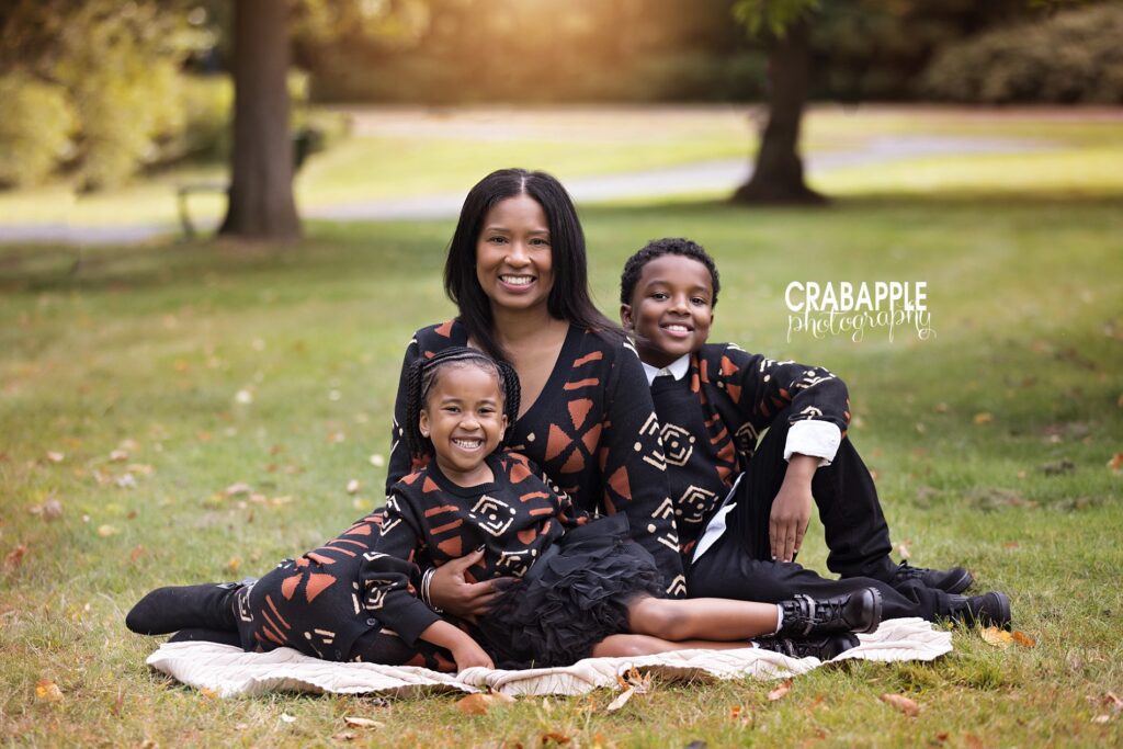 Family photo of mom and two children sitting on a blanket in the grass during family portrait session north of Boston