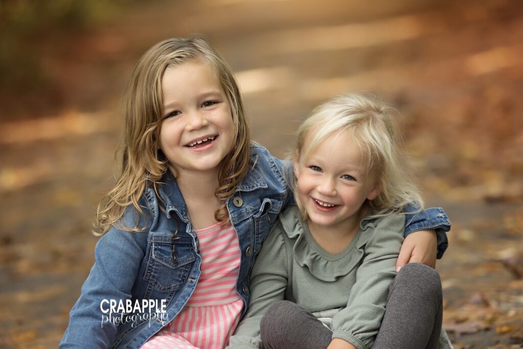Photo of two sisters laughing with fallen autumn leaves behind them