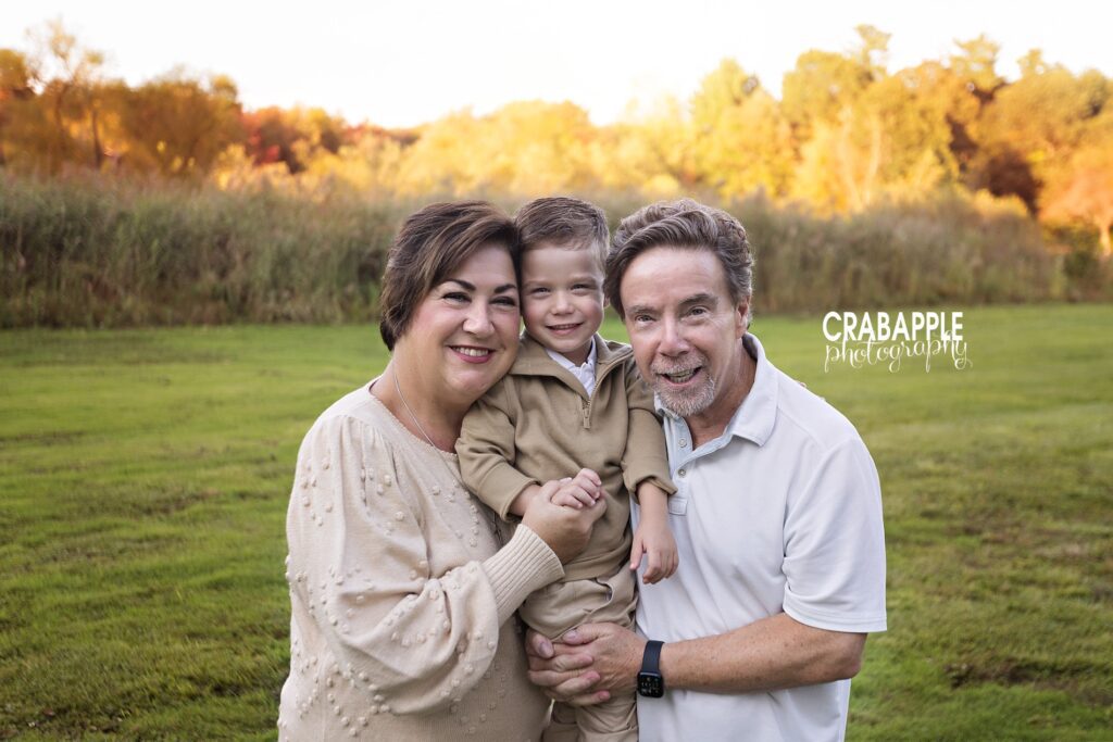 Grandparents embrace their grandson during fall extended family photos