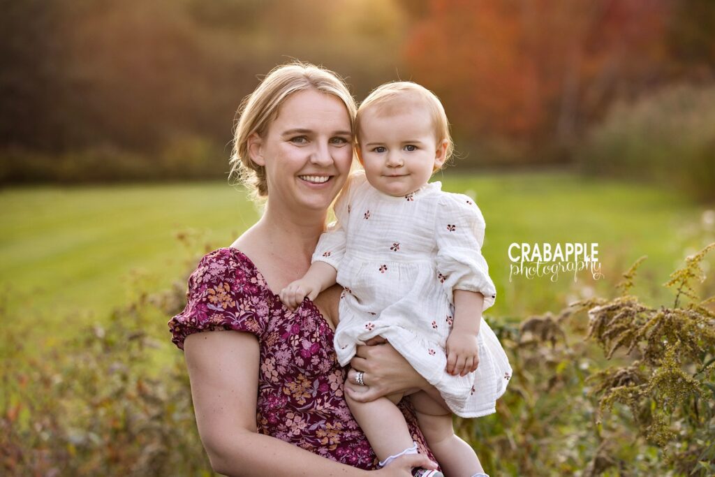 Mother and daughter portraits Mother and daughter portrait of a mom and one year old daughter smiling at the camera together near Needham MA