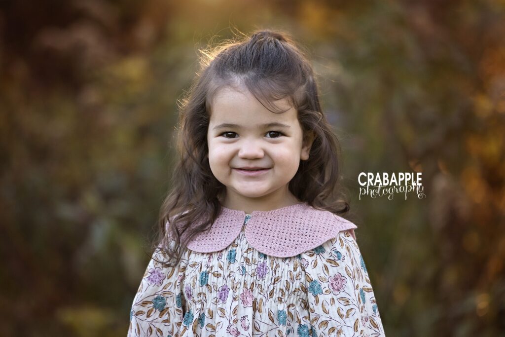 Solo portrait of younger daughter in Massachusetts fall family photos Young daughter smiling in solo outdoor fall family portrait Massachusetts