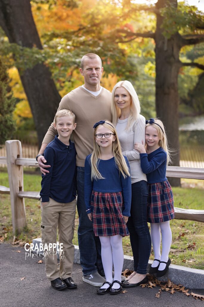 Family smiling together outdoors during fall photo session while wearing coordinating outfits