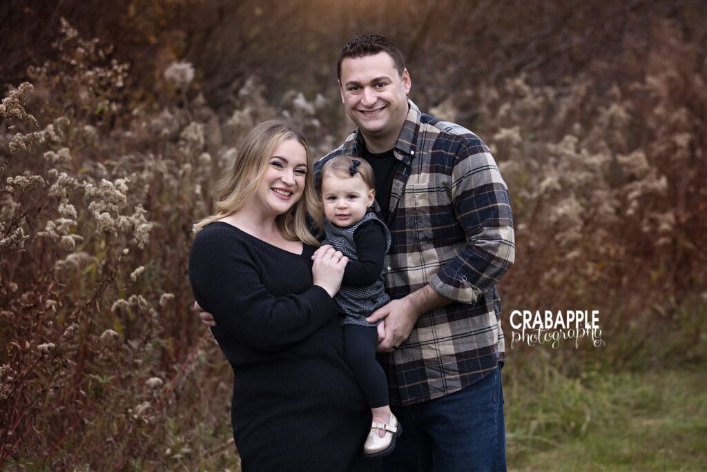 Tewksbury MA family portraits outdoors Mom and dad snuggling one year old during fall photos