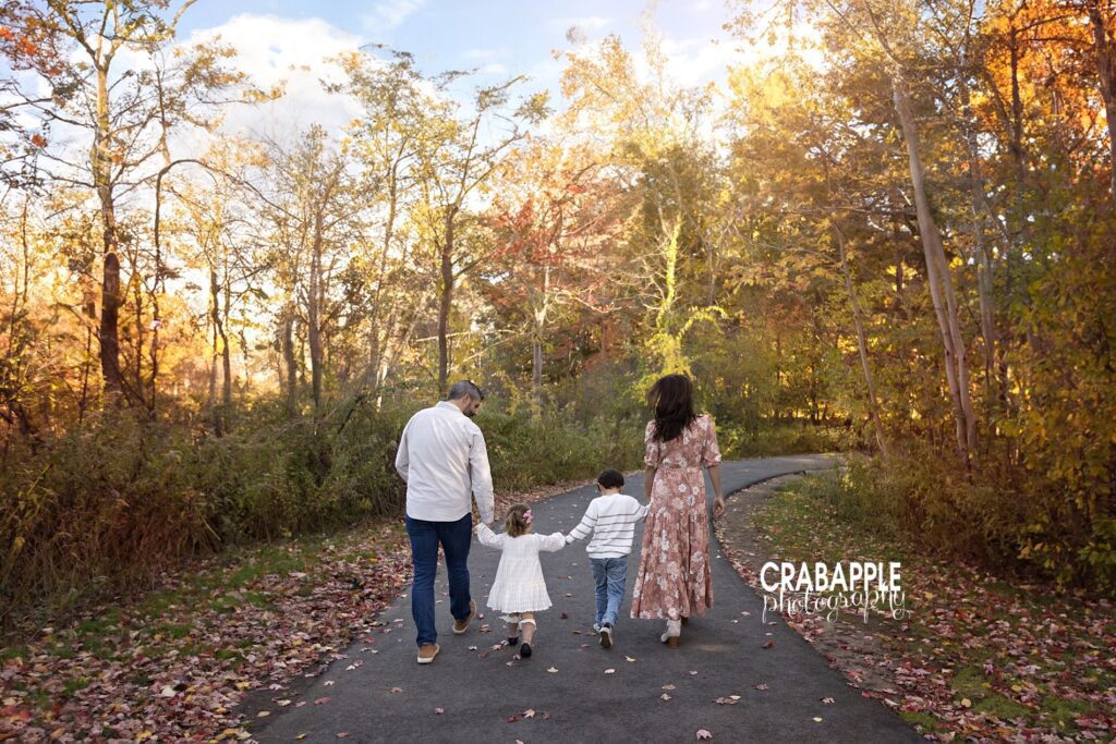 Classic outdoor family portrait poses Portrait of a family of four holding hands and walking away from the camera with a beautiful autumn backdrop