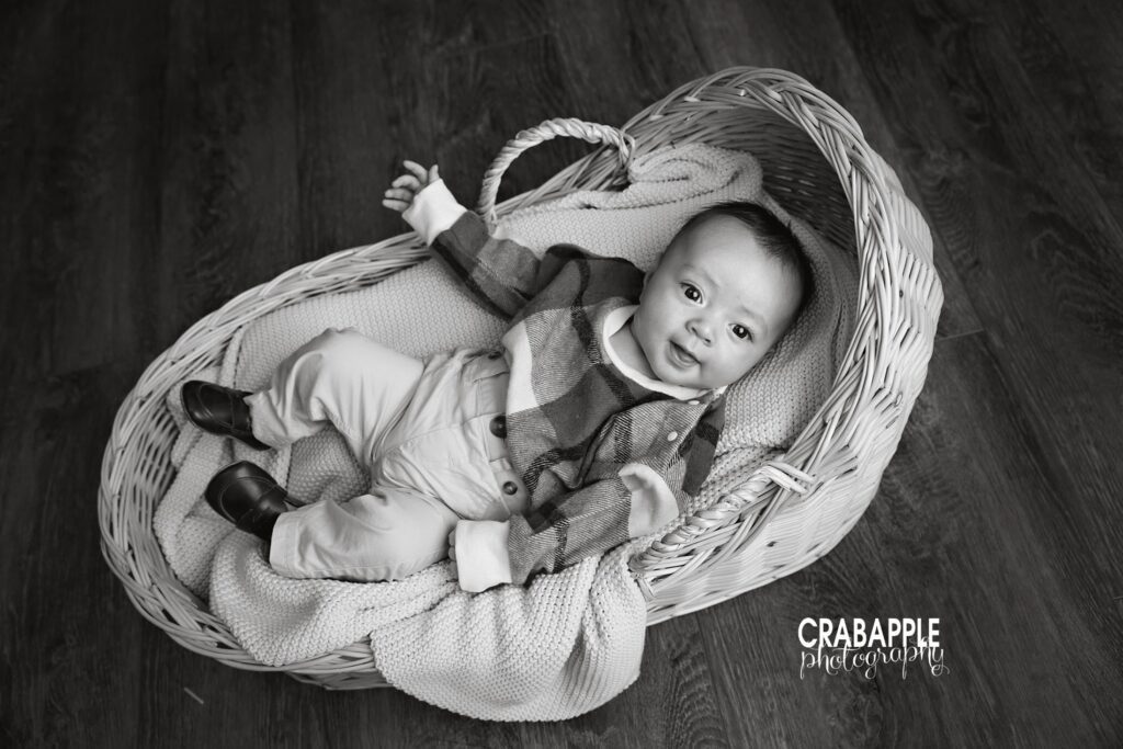 Rustic indoor fall portrait of baby boy in cozy studio. Baby boy lying in basket prop during rustic indoor fall family session.
