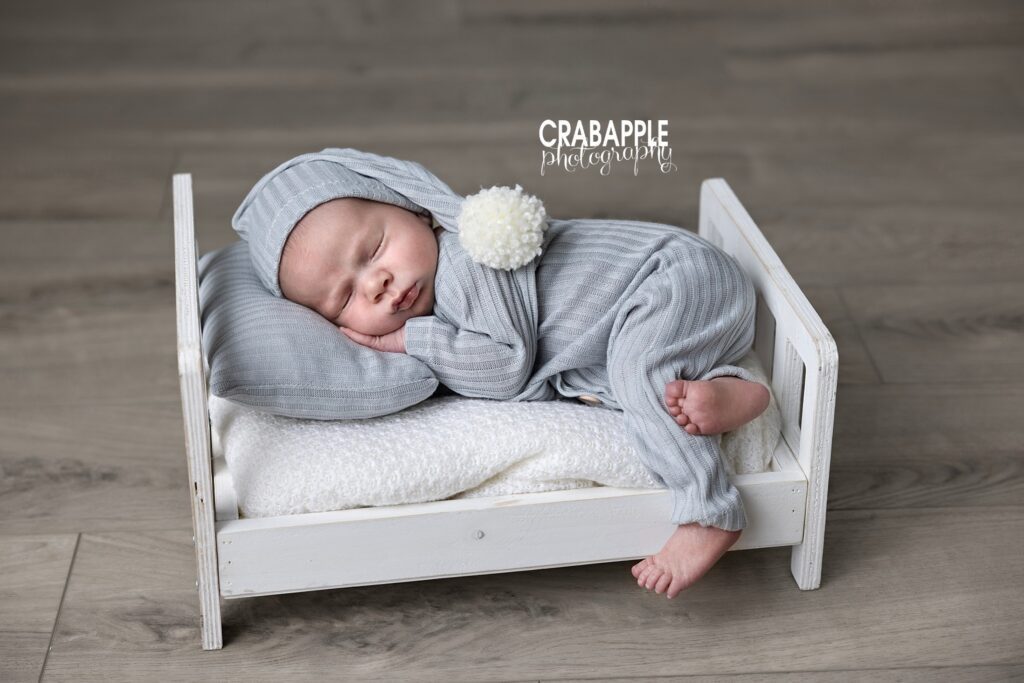 Sleeping Newborn Photography Professional portrait of a sleeping newborn baby in tiny wooden bed with gray pajamas