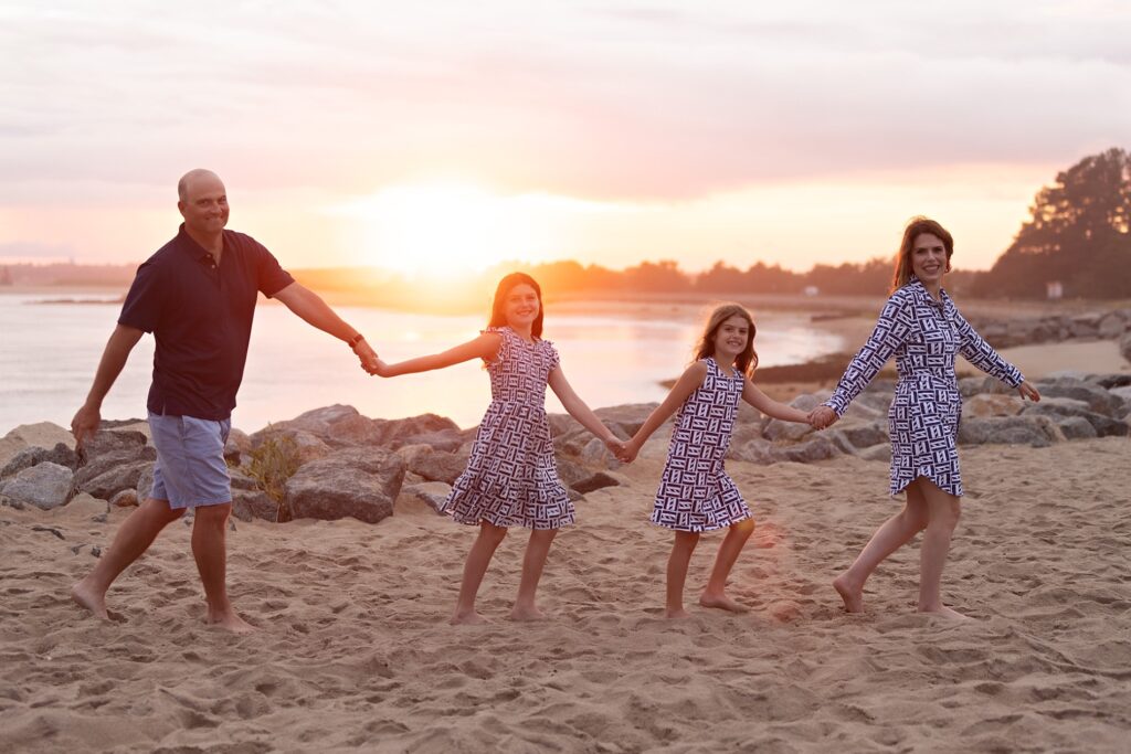 Family of four enjoying playful moments by the ocean during North Shore beach portraits
