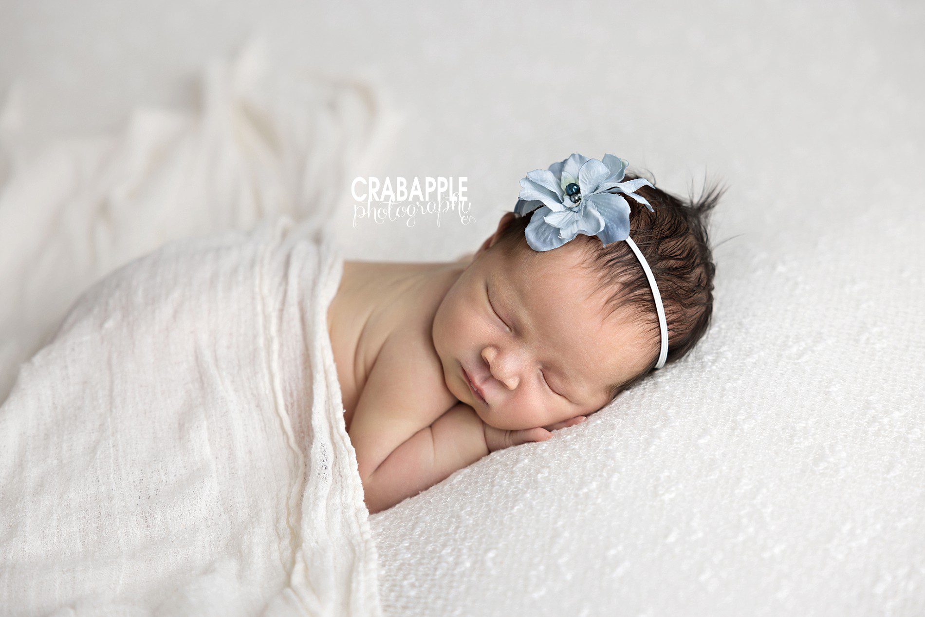 sleeping newborn baby girl studio portrait with white and pop of light blue headband