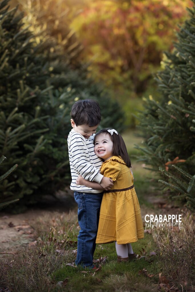 Siblings hugging during Christmas tree farm mini session