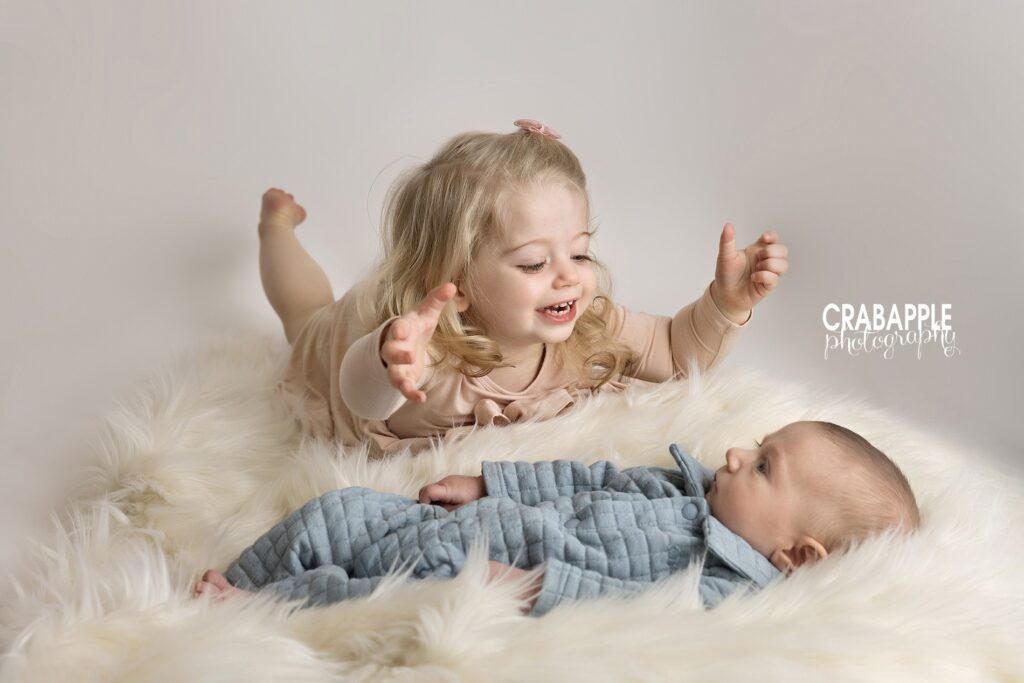 Cousin photo ideas from a winter family photo session Photo of toddler cousin smiling and looking at baby cousin in a winter family portrait session