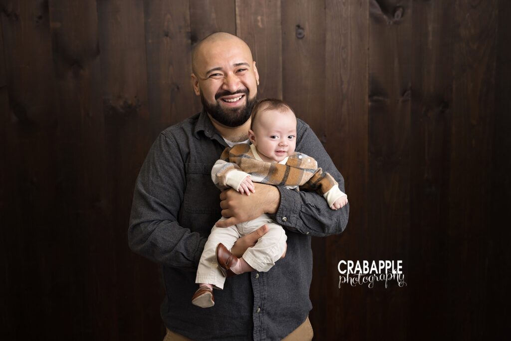 Dad and baby indoor fall family portrait in studio. Father holding baby son in cozy fall studio session with soft natural light.