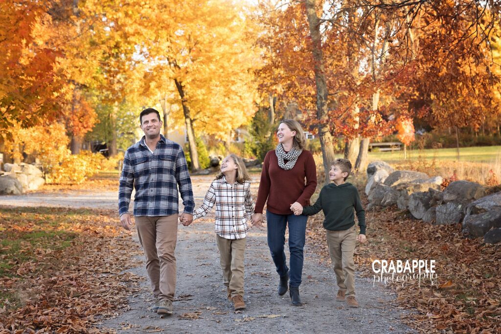 Family walking hand in hand surrounded by fallen leaves during North Shore park session
