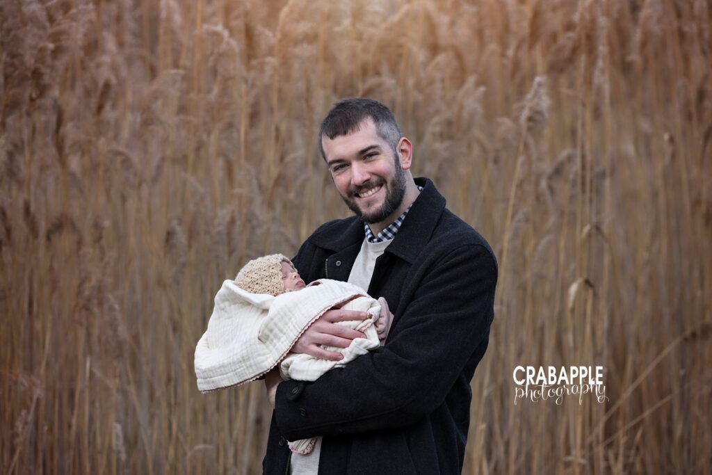 Baby wrapped in cream blanket being held close during winter family portraits
