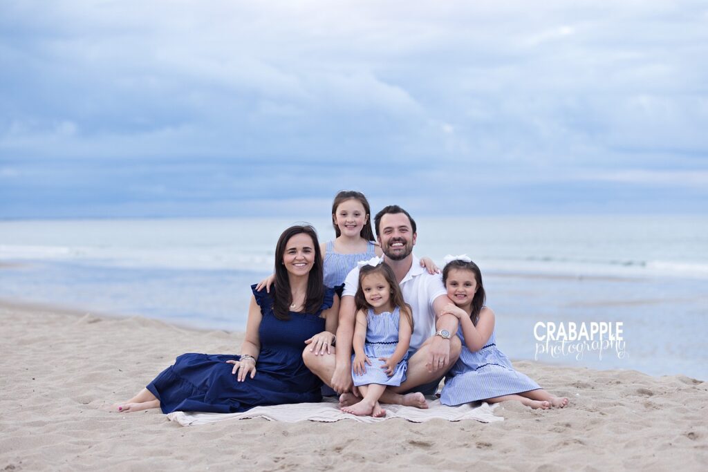 Family snuggling close with blue skies during Massachusetts beach photos
