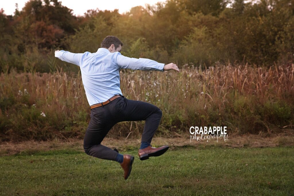 Funny candid photo of dad jumping in air and clicking his heels during outdoor fall family portraits