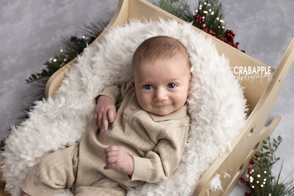 Holiday baby portraits without Santa | Wooden sleigh baby Christmas photo Close up of baby in wooden sleigh with fuzzy fur blanket for a Christmas baby photography setup.